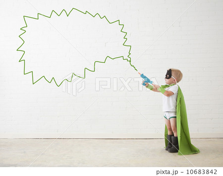 Studio shot, Portrait of boy (2-5 years) wearing green cape and holding his toy gun 10683842