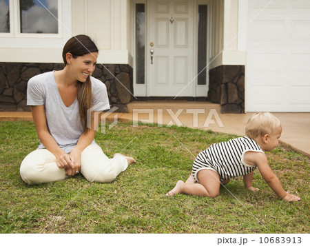 Mother with baby boy (6-11 months) in front of house 10683913