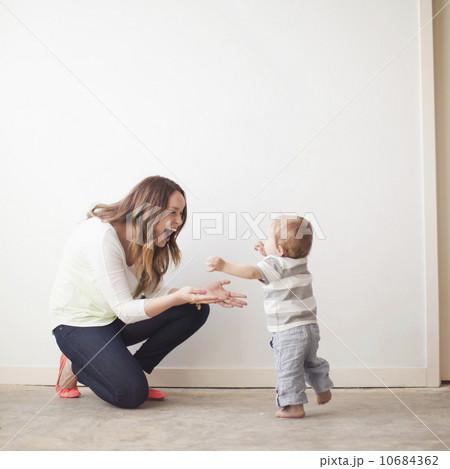Young mother assisting baby boy (6-11 months) in first steps 10684362