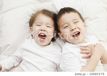 Mixed race siblings (2-3, 4-5) lying in bed side by side 10684379