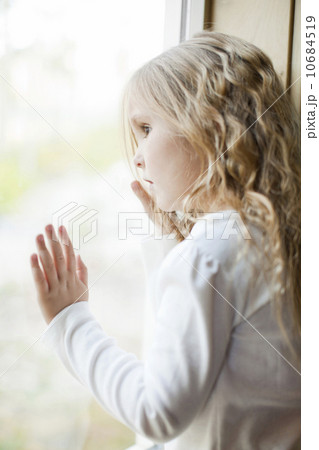 Girl (4-5) looking through window 10684519