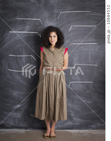 Young teacher posing against blackboard with blank lines written in chalk 10684552