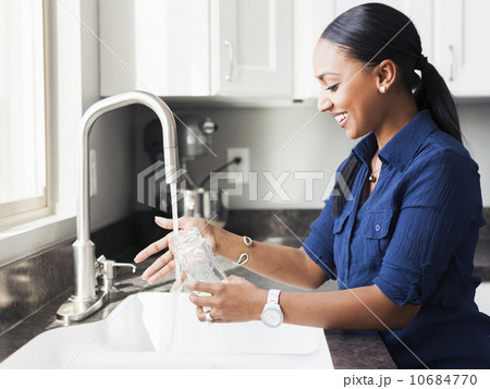 Woman washing baby bottle in kitchen 10684770