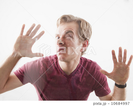 Man pushing his face and hands against glass 10684997