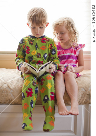 Brother (6-7) and sister (4-5) reading book together Brother (6-7) and sister (4-5) reading book together 10685482