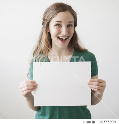 Portrait of young attractive woman holding blank sheet of paper Portrait of young attractive woman holding blank sheet of paper 10685934