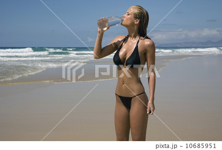 Attractive young woman drinking water on beach Attractive young woman drinking water on beach 10685951