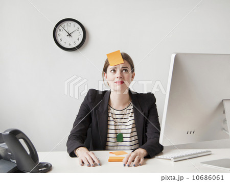 Studio shot of young woman working in office with adhesive note on her forehead 10686061