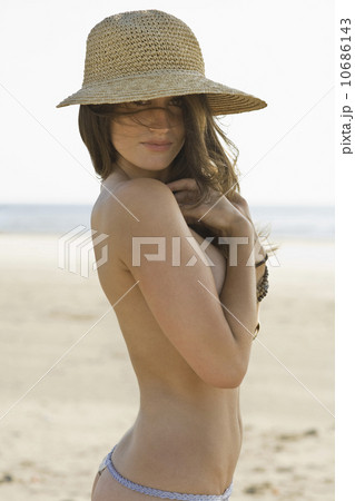 Shirtless woman posing on beach 10686143