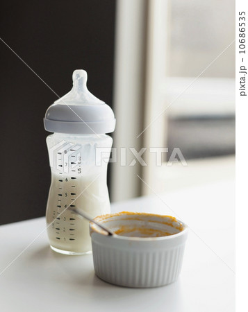 Milk in baby bottle and small bowl on table 10686535