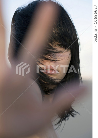 Naked young woman covering camera lens with hang 10686627