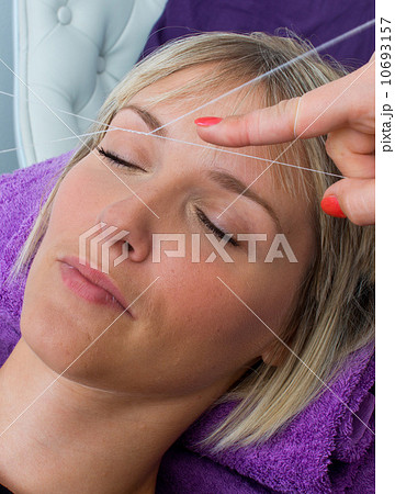 woman having threading hair removal procedure 10693157
