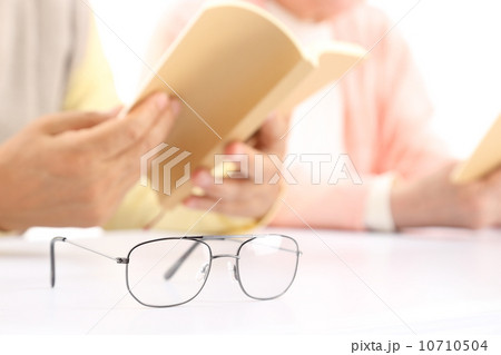 老眼鏡と本を読むシニアの手 10710504