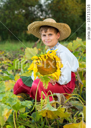 Young happy boy hold sunflower in a garden Young happy boy hold sunflower in a garden 10715116