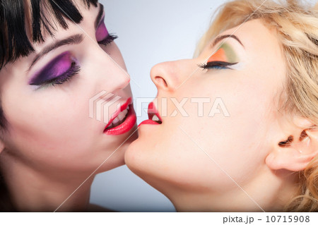 Two young attractive lesbians kissing isolated on gray backgroun 10715908