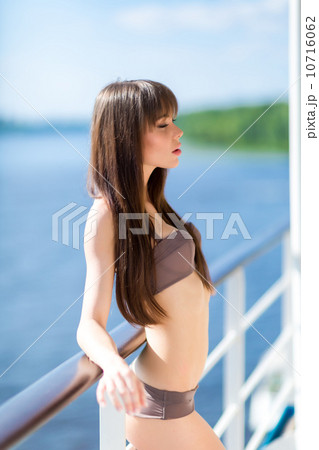 Sexy woman in stylish swimsuit standing on the aft of a sailing Sexy woman in stylish swimsuit standing on the aft of a sailing 10716062