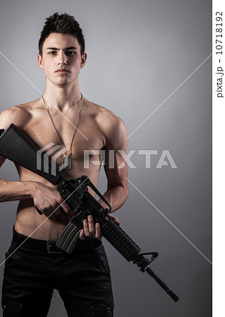Handsome bare-chested soldier is holding a rifle 10718192