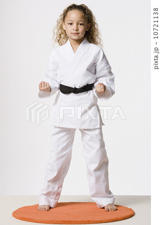 Studio portrait of smiling girl (8-9) wearing gi 10721138
