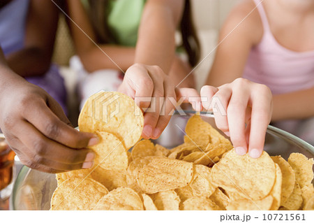 Three girls (10-11) reaching for crisps Three girls (10-11) reaching for crisps 10721561