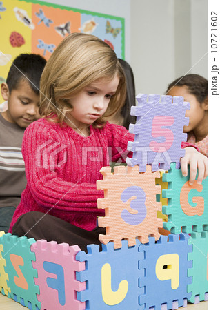 Girls (6-7) playing with puzzle letters 10721602