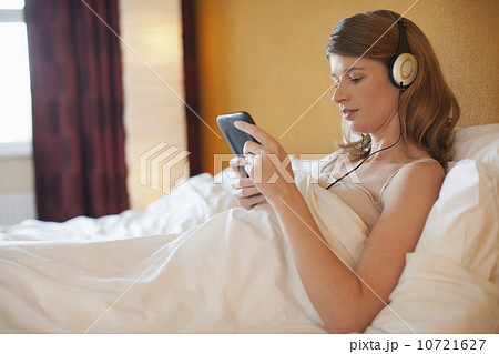 Young pregnant woman listening to music in bed Young pregnant woman listening to music in bed 10721627
