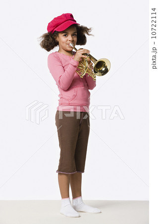 Studio portrait of girl (8-9) playing trumpet 10722114