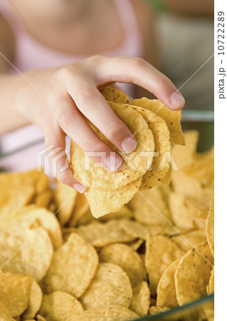 Close up of girl's (10-11) hand taking potato chips from bowl Close up of girl's (10-11) hand taking potato chips from bowl 10722289