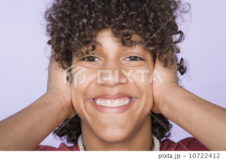 Portrait of teenage boy (14-15) covering ears with hands 10722412