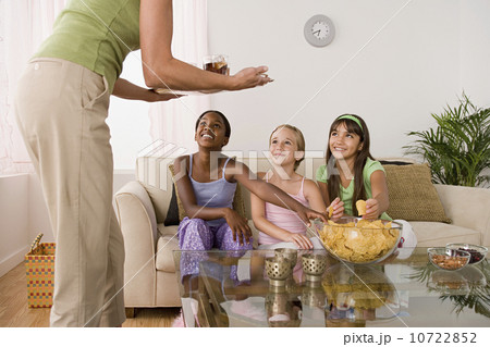 Woman serving food for three girls (10-11) at slumber party 10722852