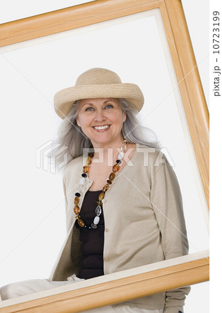 Studio portrait of mature woman behind picture frame 10723199