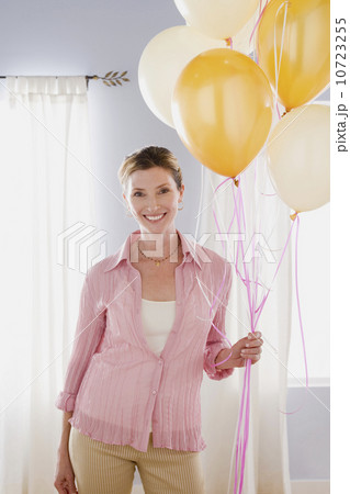 Woman in pink blouse holding balloons 10723255