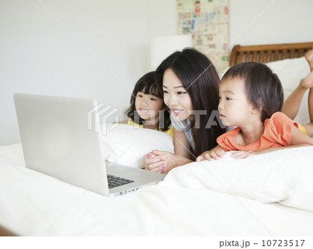 Mother with daughters (2-3, 4-5) lying down in bed, using laptop Mother with daughters (2-3, 4-5) lying down in bed, using laptop 10723517