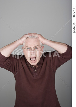 Studio shot portrait of senior man with head in hands and open mouth, waist up Studio shot portrait of senior man with head in hands and open mouth, waist up 10724138