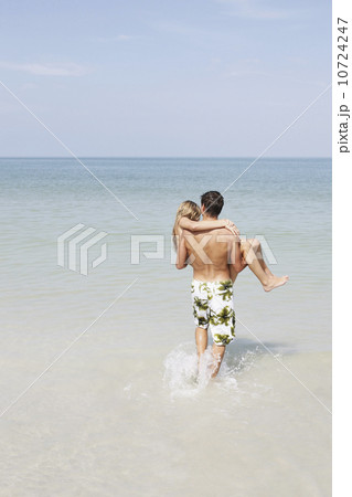 Teenage boy carrying girlfriend in ocean 10724247