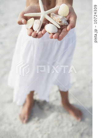 Girl on beach holding delicate starfish and shells 10724309