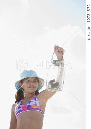Girl at beach displaying jar of shells Girl at beach displaying jar of shells 10724379