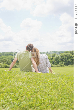 Couple sitting on grass and looking at view 10724442