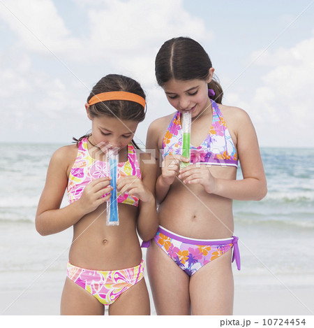 Girls eating ice pops on beach Girls eating ice pops on beach 10724454
