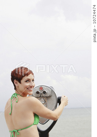 Woman looking through coin-operated binoculars 10724474