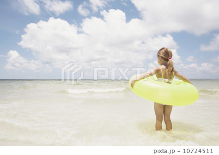 Girl carrying inflatable ring into ocean 10724511