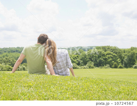 Couple sitting on grass and looking at view 10724567