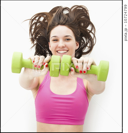 Studio portrait of young woman holding hand weights Studio portrait of young woman holding hand weights 10724799