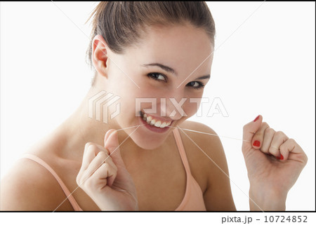 Studio portrait of young woman flossing teeth Studio portrait of young woman flossing teeth 10724852