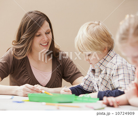 Mid adult woman teaching boy (4-5) drawing in kindergarten Mid adult woman teaching boy (4-5) drawing in kindergarten 10724909