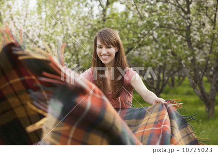 Young woman holding blanket in orchard Young woman holding blanket in orchard 10725023
