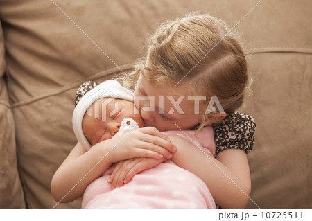Girl (2-3) embracing baby sister on sofa Girl (2-3) embracing baby sister on sofa 10725511