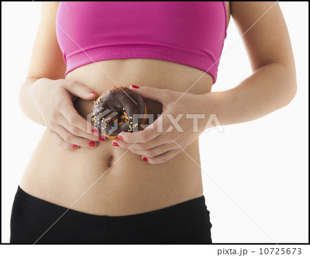 Young woman holding doughnut against belly 10725673