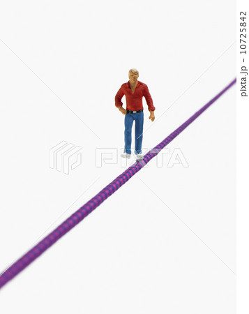 Studio shot of male figurine balancing on tightrope 10725842
