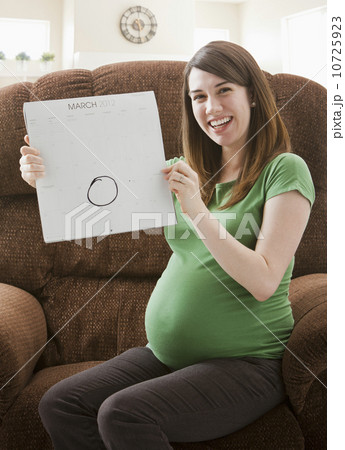Portrait of pregnant woman showing calendar with due date Portrait of pregnant woman showing calendar with due date 10725923