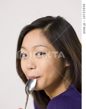 Young woman chewing spoon 10725936